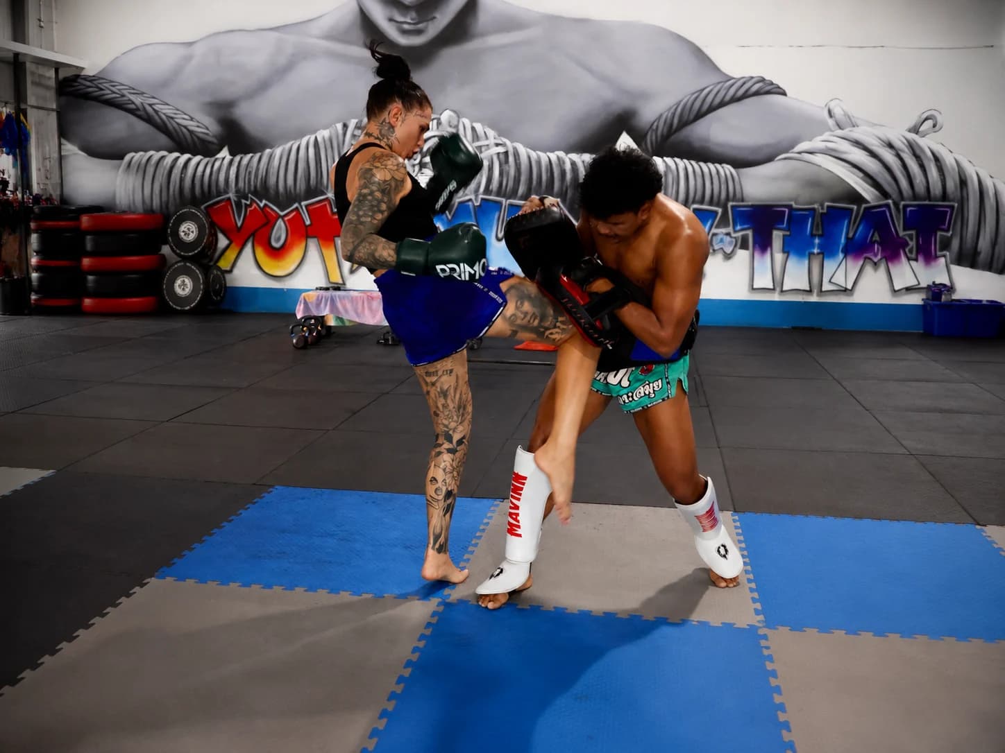 Combattante de Muay Thai portant un coup de genou en clinch à l'entraînement devant la fresque Yodyut Muay Thai à Koh Samui