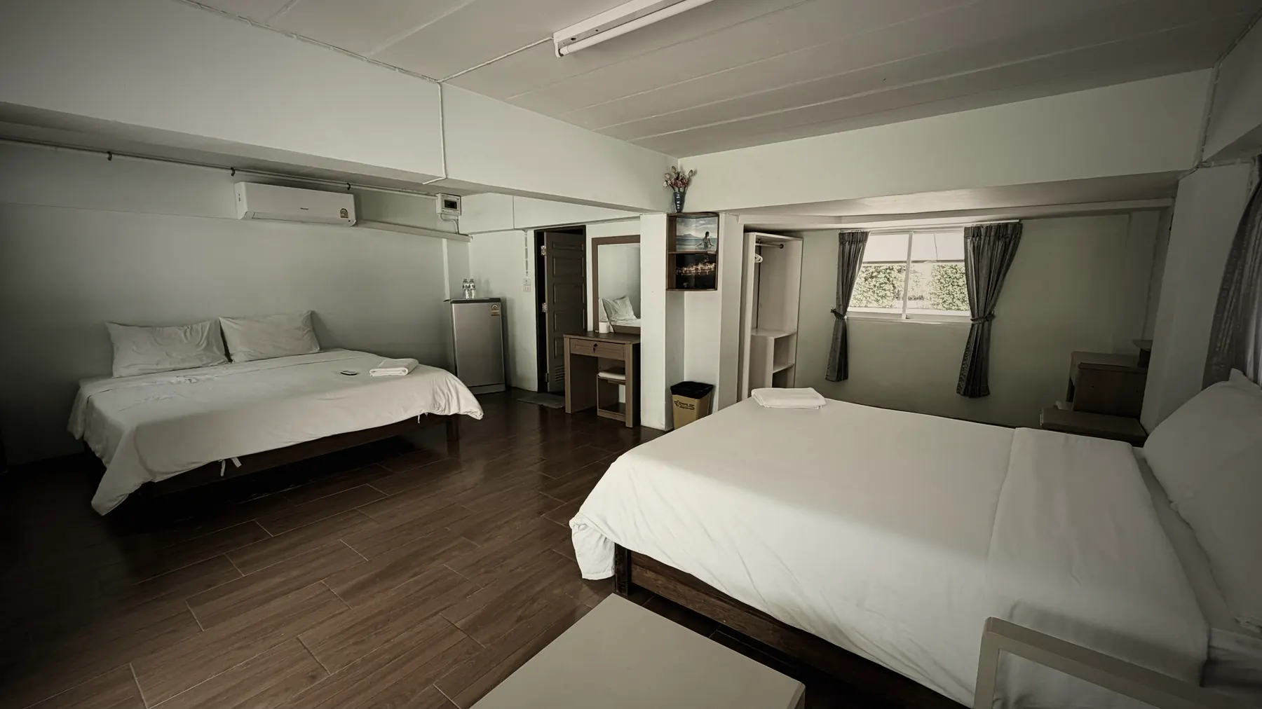 Chambre du logement Road to Fight à Koh Samui avec deux lits, climatisation et sol en bois